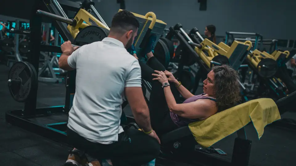 Trainer adjusting a client on a machine